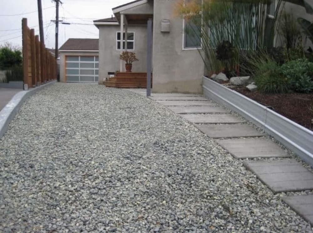 Gravel driveway with inset concrete stepping pads running beside a house to the garage.
